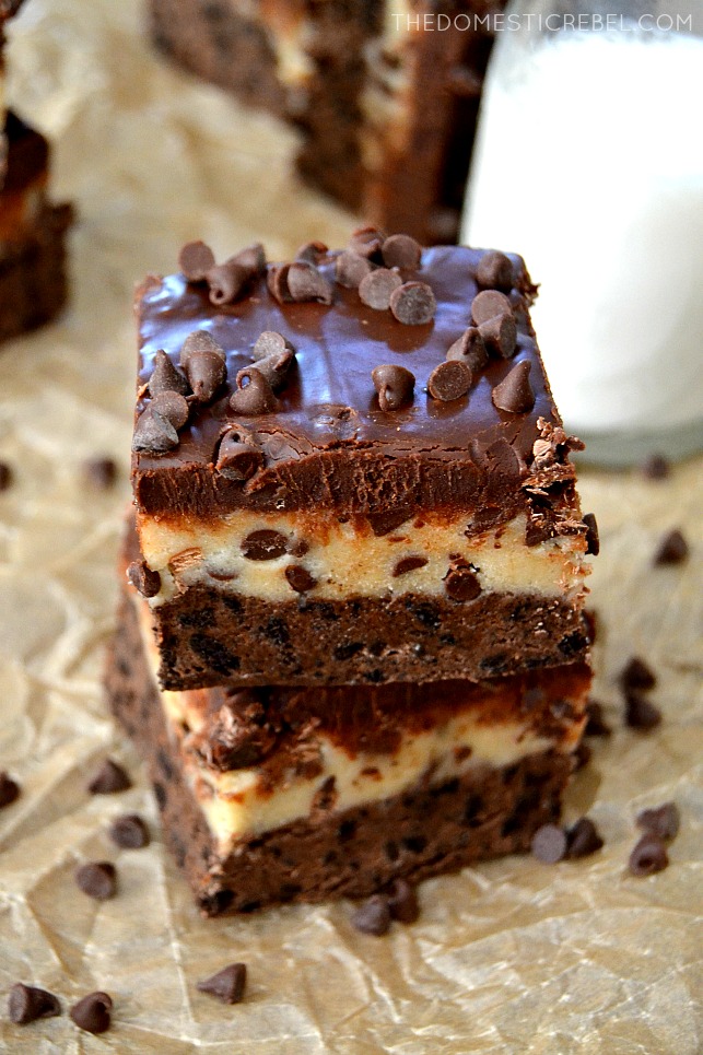 Cookie Dough Brownies stacked on parchment with chocolate chips