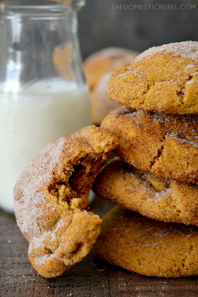 Pumpkin Snickerdoodles stacked with bite missing in front of milk glass