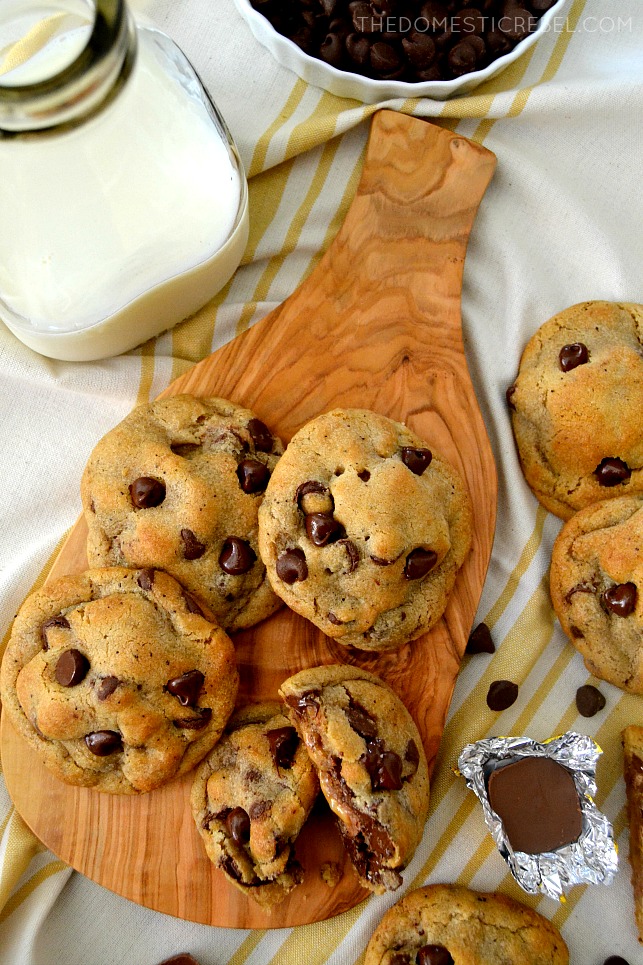 Chocolate Chip Caramel Cookies arranged on wood board with milk and candy