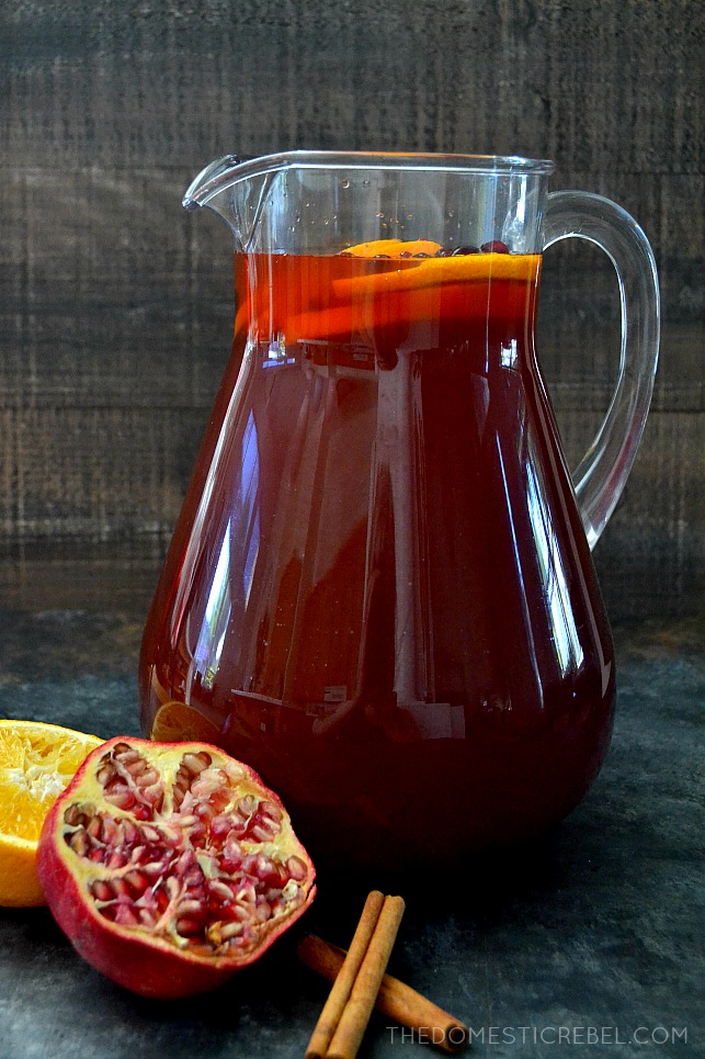 Pitcher filled with tea with pomegranate, cinnamon sticks and orange