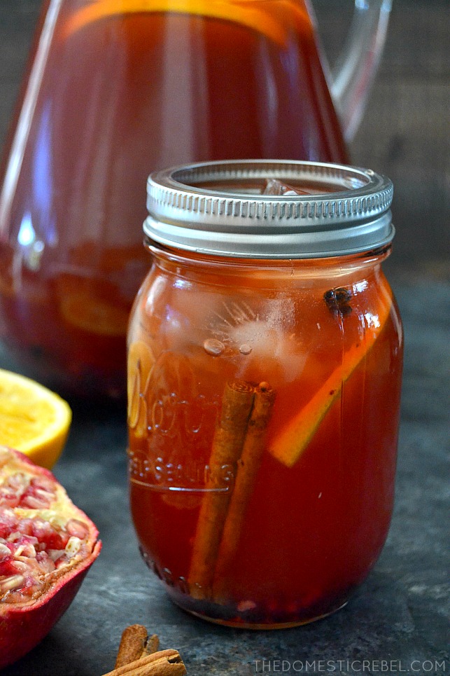 Glass of Pomegranate Orange Iced Tea in Mason jar with oranges and pomegranates