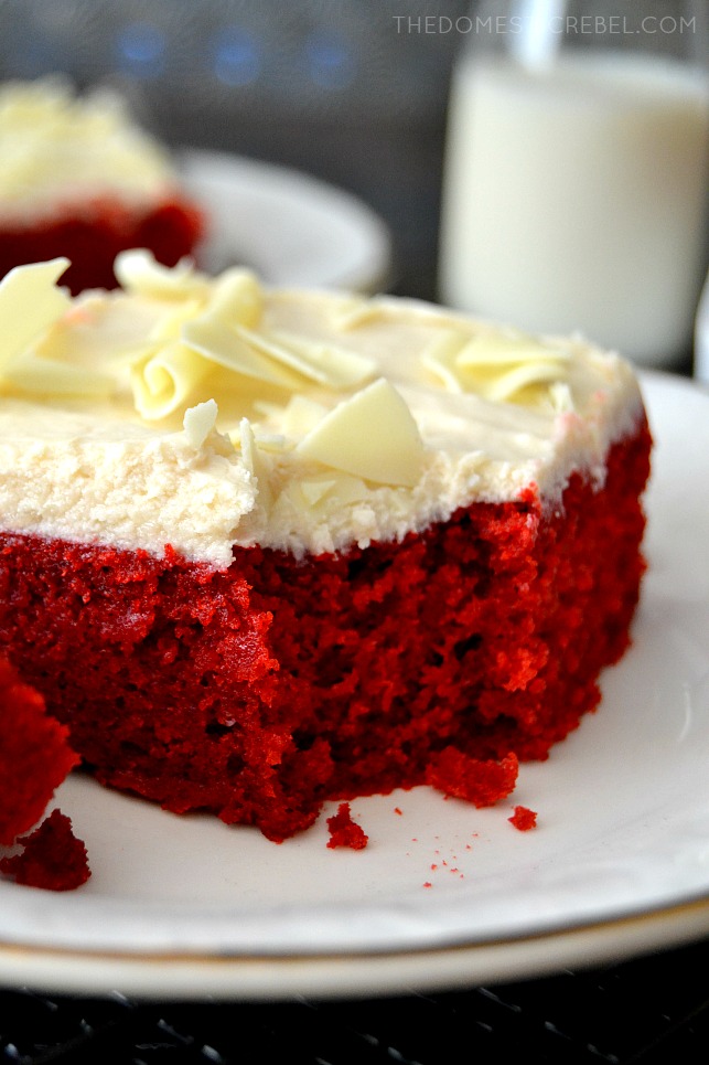 closeup of red velvet cake slice with bite missing on white plate