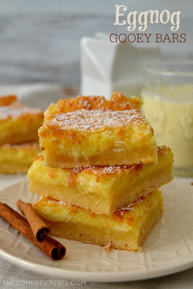 eggnog gooey bars stacked on white plate with cinnamon sticks