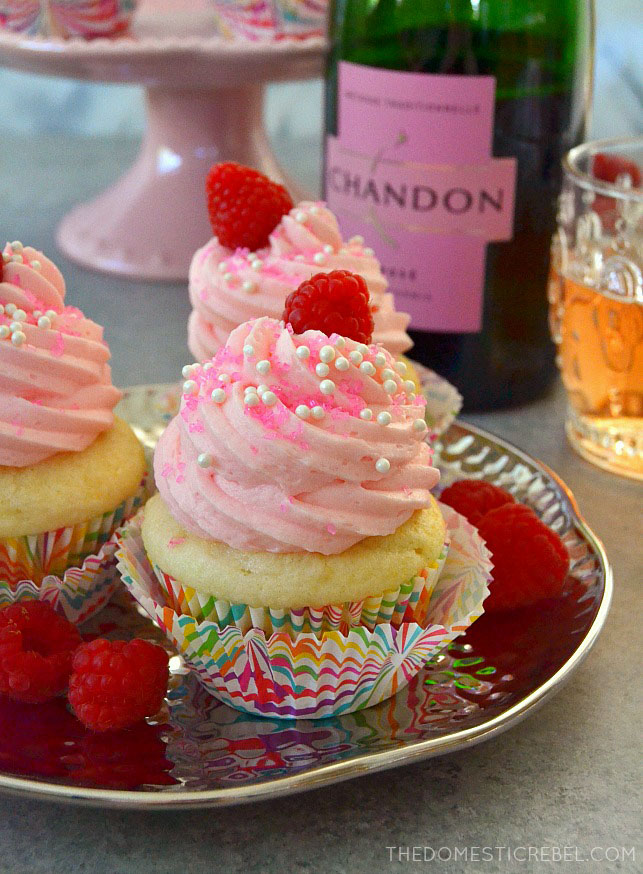 pink champagne cupcakes with champagne in background