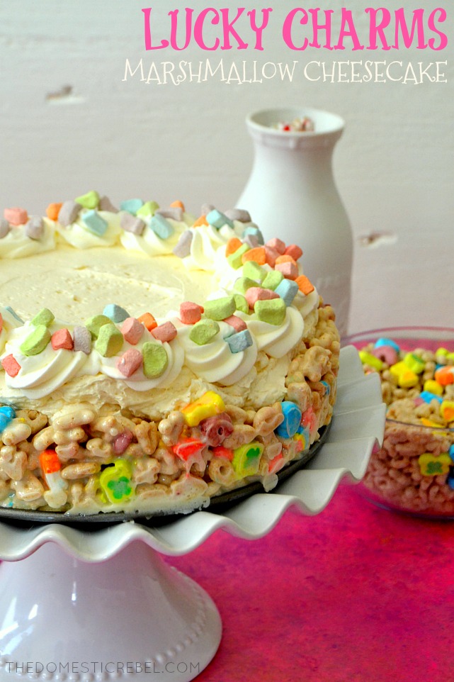 A SIDE VIEW OF THE LUCKY CHARMS MARSHMALLOW CHEESECAKE ON A CAKE STAND.