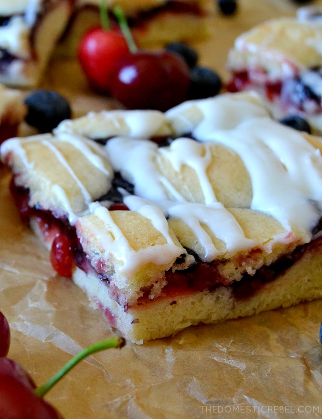 ONE SLICE OF BLUEBERRY PIE BAR ON PARCHMENT PAPER WITH CHERRIES