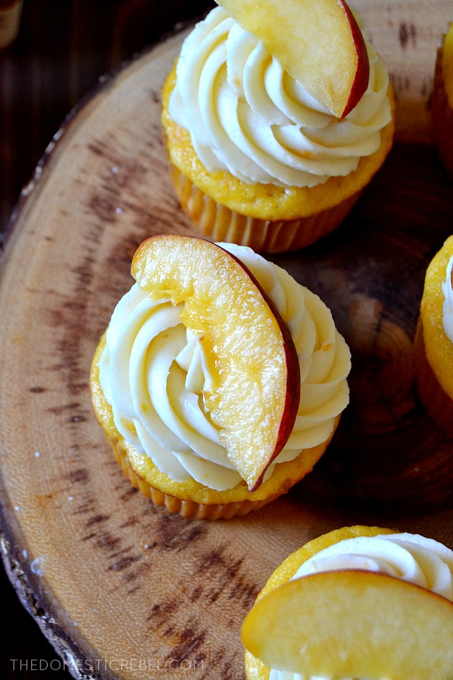 PEACH BOURBON CUPCAKES ARRANGED ON A WOODEN CAKE STAND