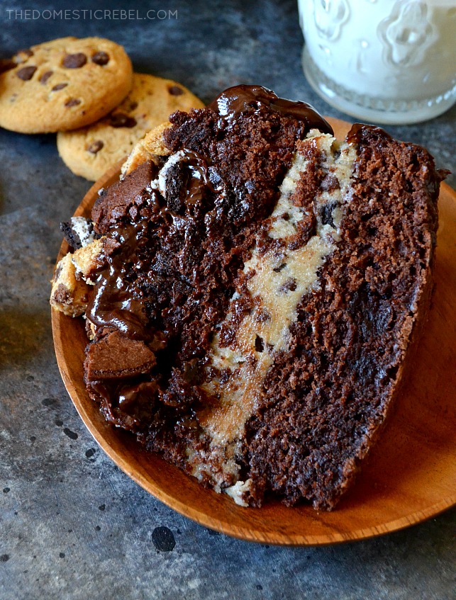 SLICE OF SLUTTY BROWNIE COOKIE DOUGH CAKE WITH COOKIES IN BACKGROUND