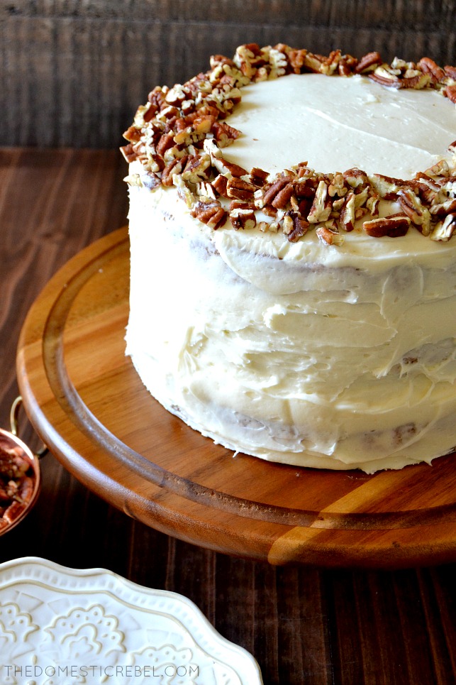 side view of the whole butter pecan layer cake on a wooden cake stand