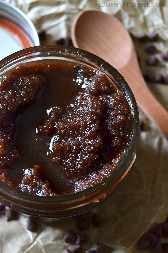chocolate sugar scrub in a jar next to a wooden spoon 