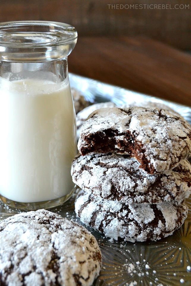 three chocolate crinkle cookies stacked next to a glass of milk