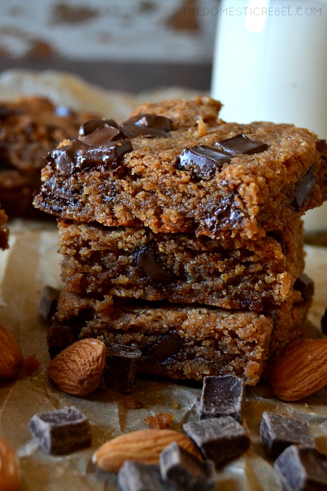 three blondies stacked on parchment with almonds and chocolate chunks