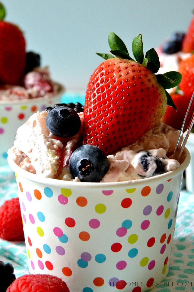 berry cheesecake fluff in a polka dot bowl topped with blueberries and strawberries