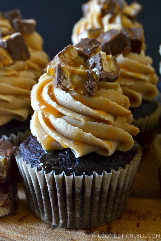 A Snickers cupcake topped with chopped Snickers and caramel drizzle