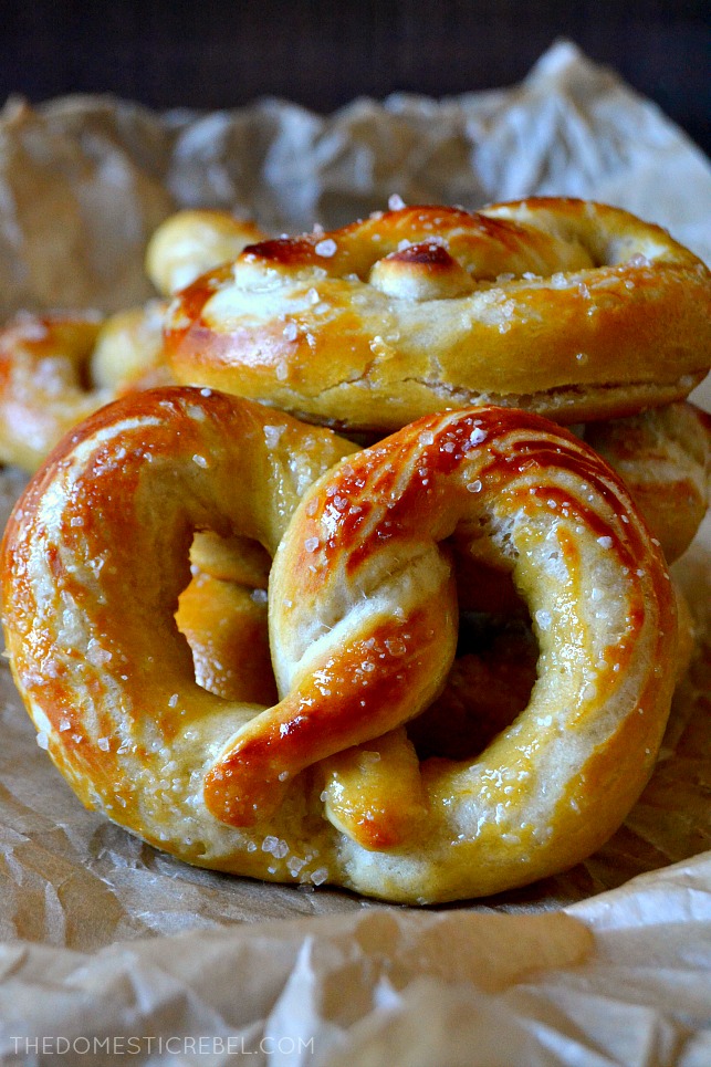 One soft pretzel propped against a stack of pretzels 