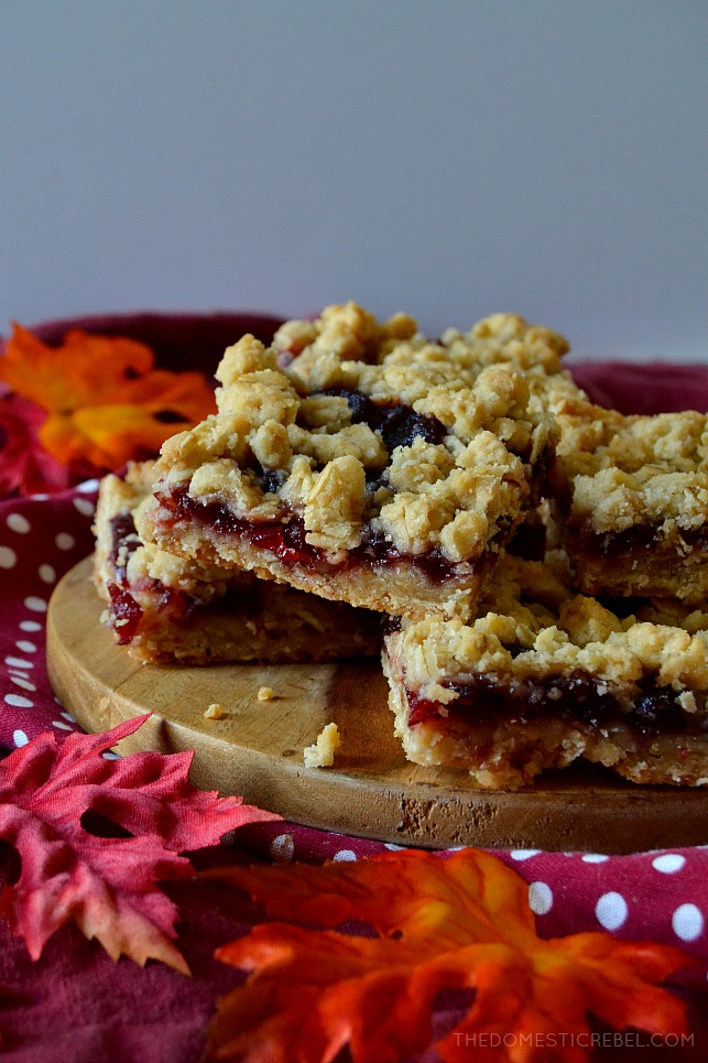 Cranberry crumble bars on a wooden circle sitting on top of a red polka dot towel