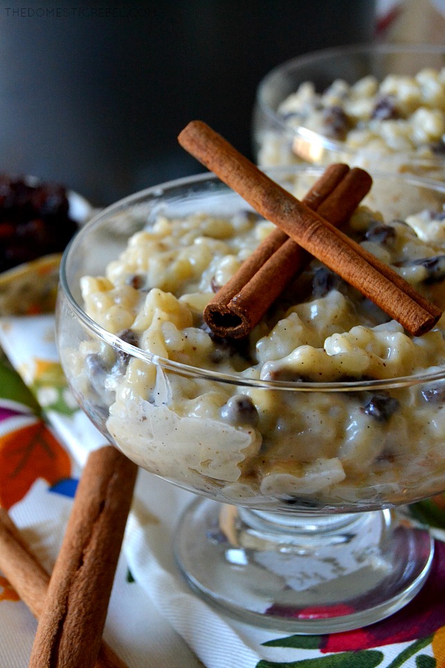 Close up of rice pudding in a glass dish next to cinnamon sticks