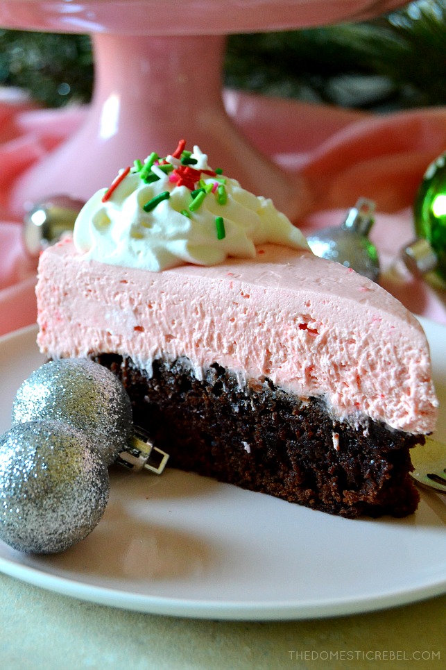 Slice of peppermint brownie cheesecake on a white plate next to ornaments
