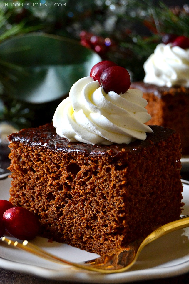 Close-up of a square of gingerbread cake with whipped cream and a golden fork