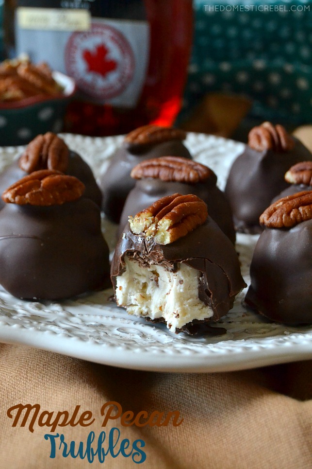 An array of maple pecan truffles on a white plate with a bite missing from one to show the inside