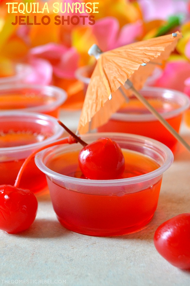 tequila sunrise jello shots in small containers with paper umbrella and cherries