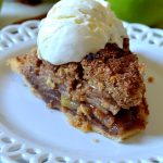 slice of apple crisp pie with a scoop of vanilla ice cream on a white lacy plate