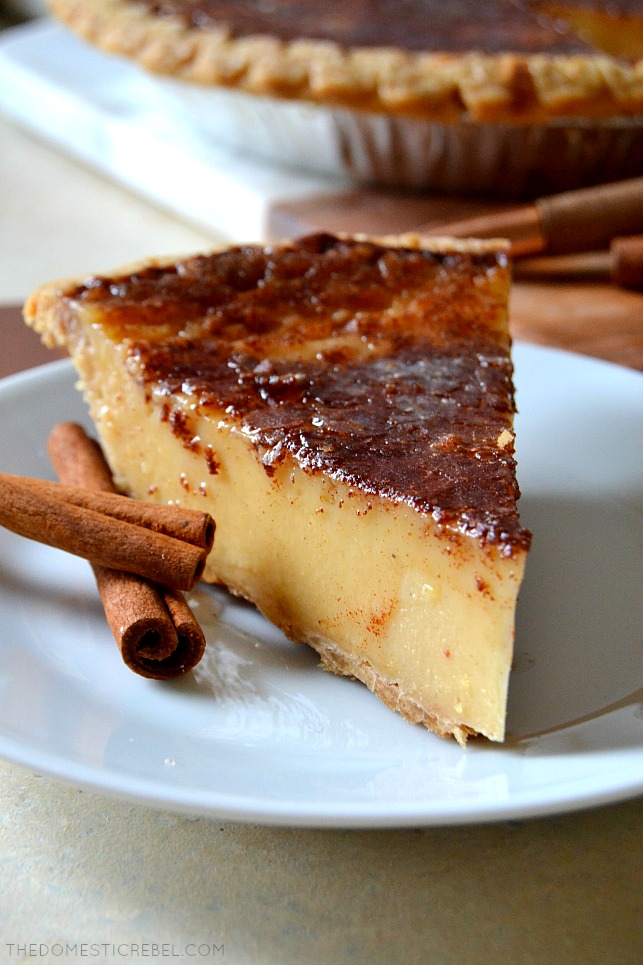 closeup of eggnog brulee pie slice on white plate with cinnamon sticks