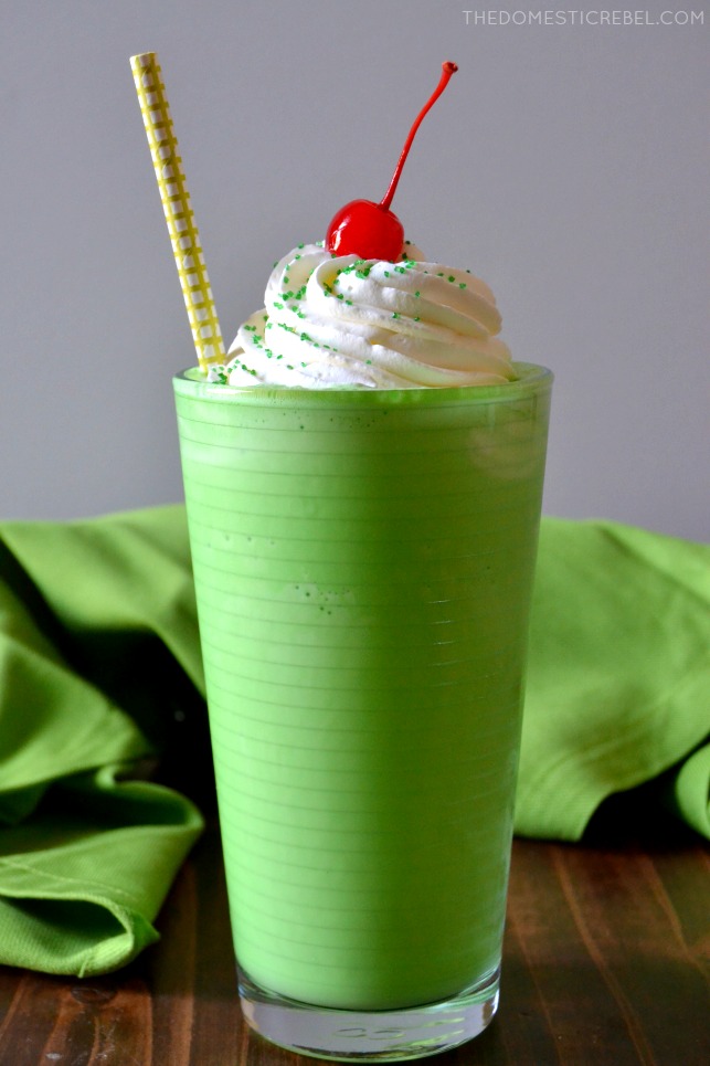 copycat shamrock shake in clear glass with straw and cherry with green fabric
