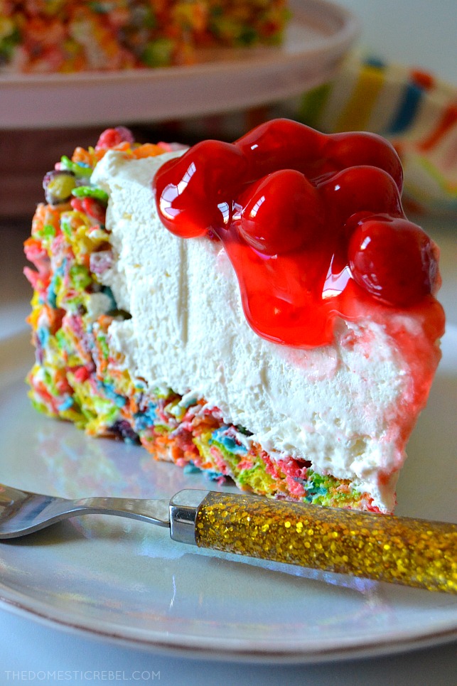 closeup of fruity pebbles cheesecake slice on white plate with gold fork