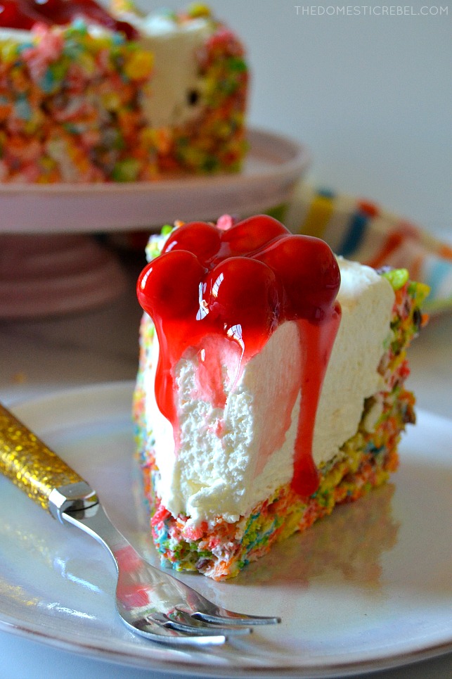 fruity pebbles cheesecake slice with bite missing on white plate with gold fork