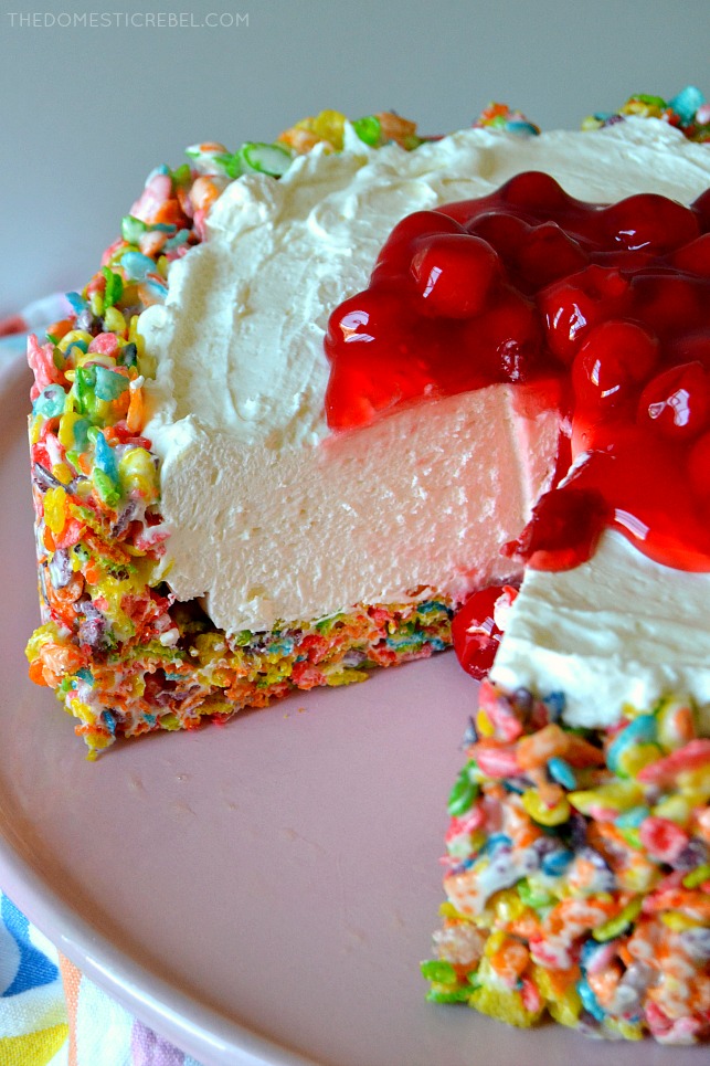 fruity pebbles cheesecake with slice missing on pink cake plate