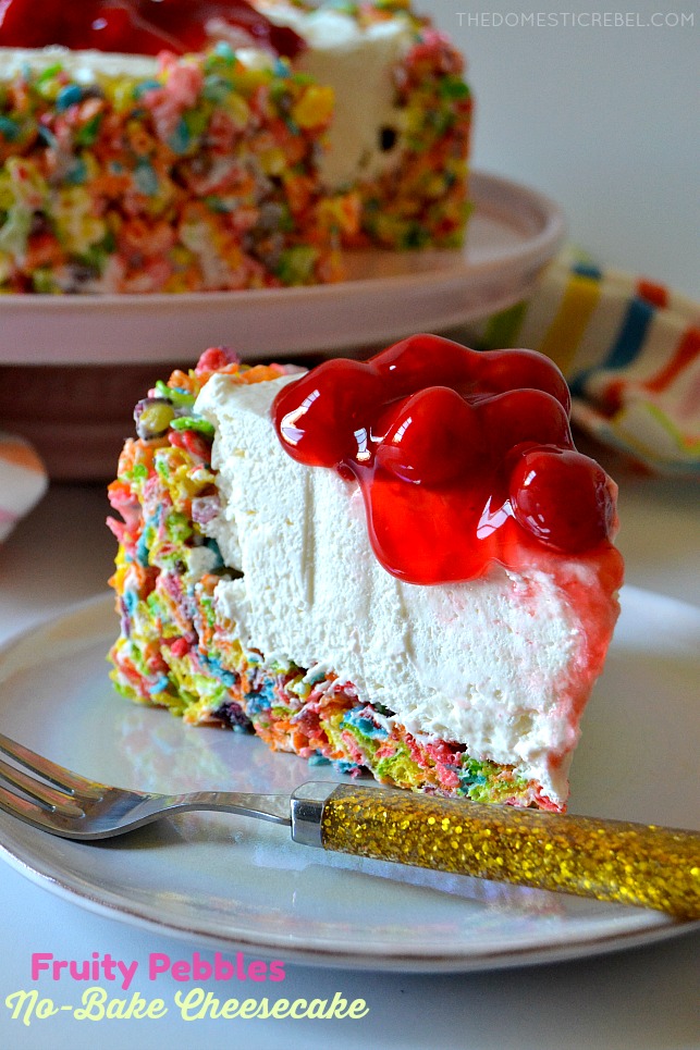 fruity pebbles cheesecake slice on white plate with gold sparkle fork