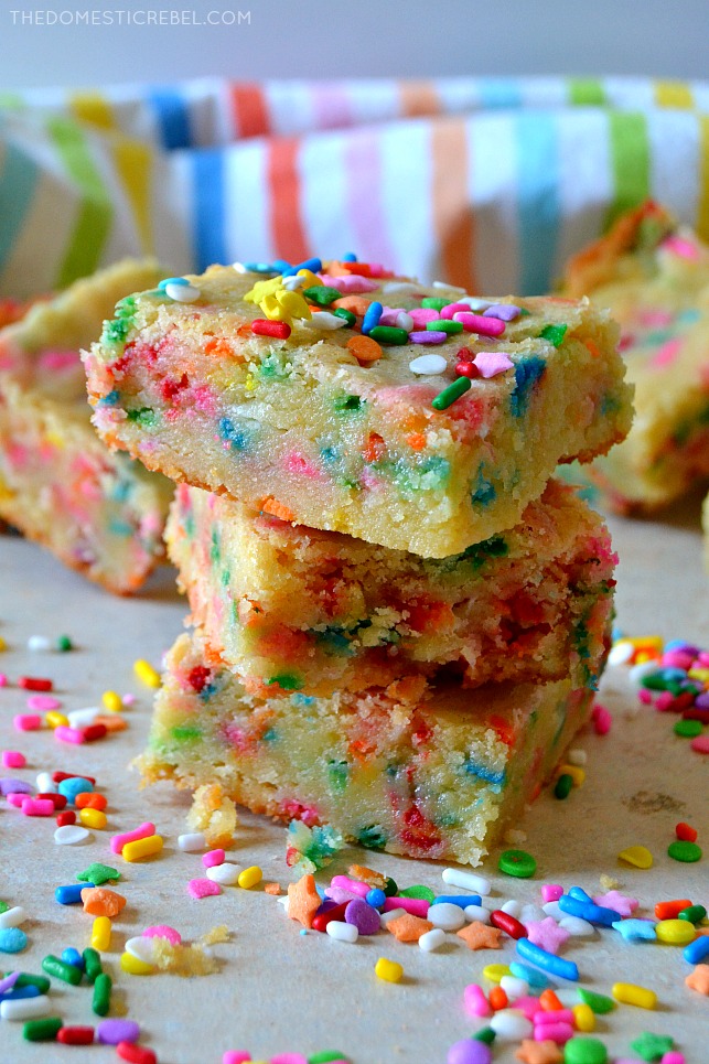 a trio of cake batter blondies stacked on wood with sprinkles