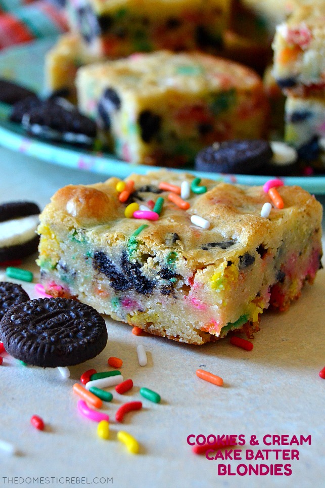 Single cookies & cream cake batter blondie on white wood with sprinkles and oreos