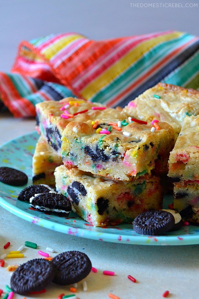 Blue plate filled with cookies & cream cake batter blondies with colorful fabric in backvground