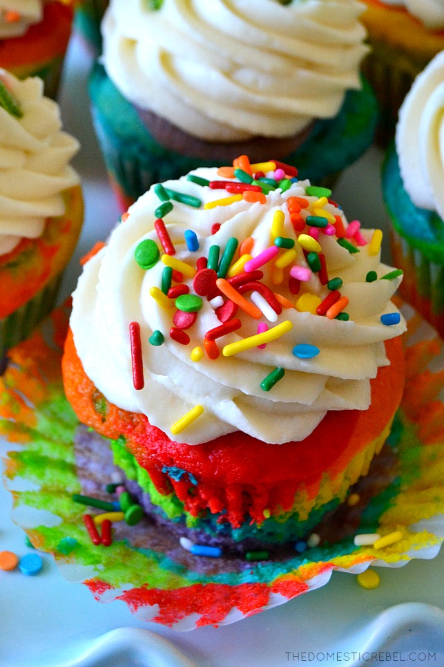 Photo of Rainbow Cupcake with sprinkled frosting on blue cake stand