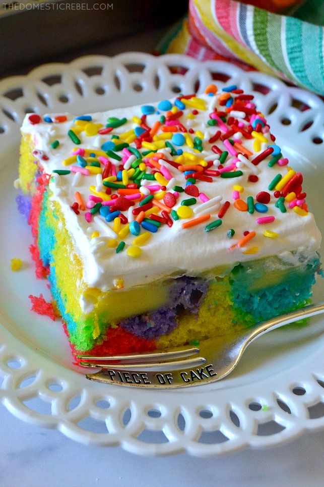 Photo of Rainbow Poke Cake on white lacy plate with fork
