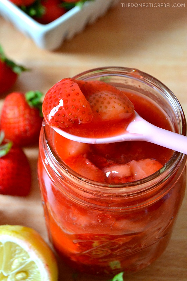 Jar of strawberry sauce with spoon resting on mouth of jar