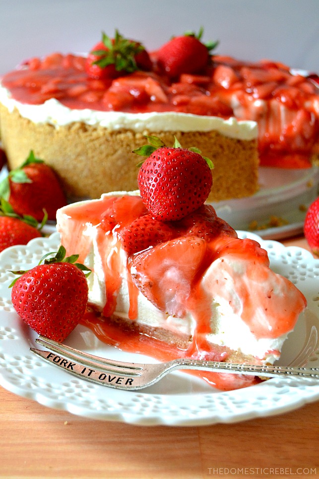 Slice of Strawberry Cheesecake on white plate with silver fork and small strawberry