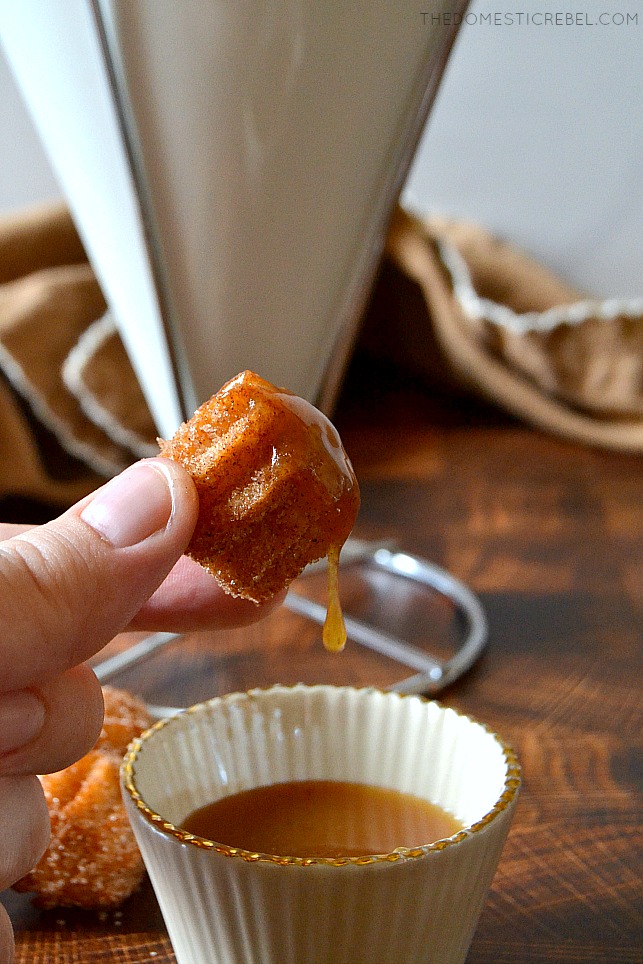 Photo of author holding a churro bite dipped in caramel sauce