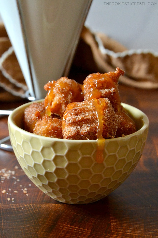 Churro bites in a small tan bowl with caramel dripping over them