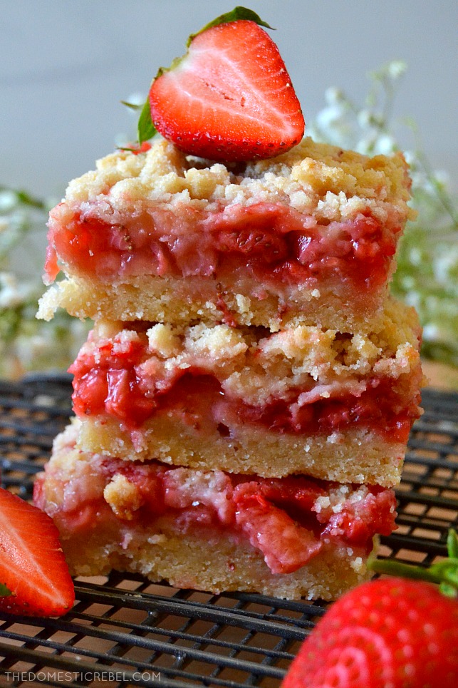 three stack of strawberry crumble bars on wire rack with fresh berries