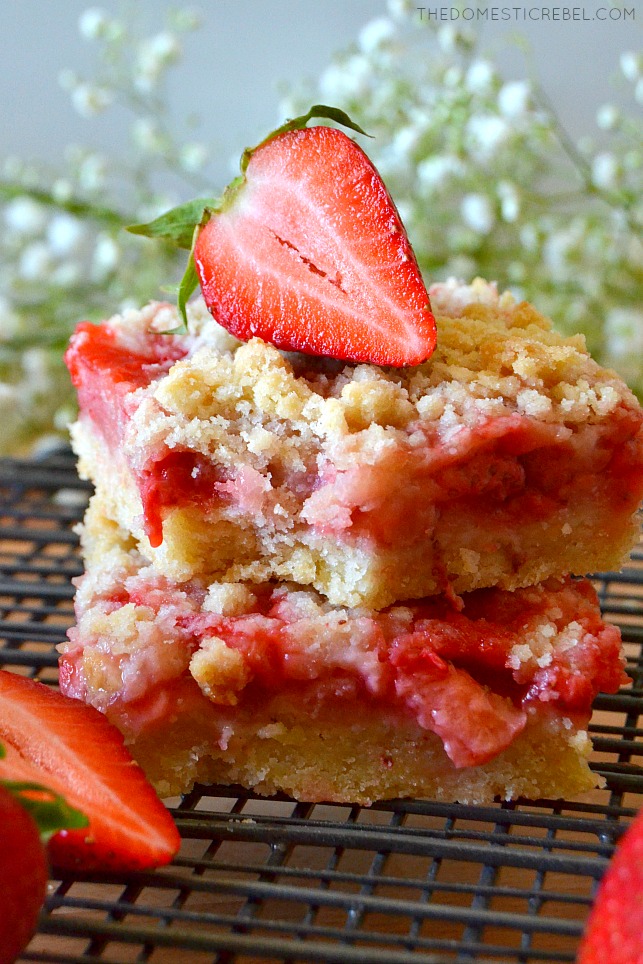 stack of strawberry crumble bars on wire rack with a bite missing