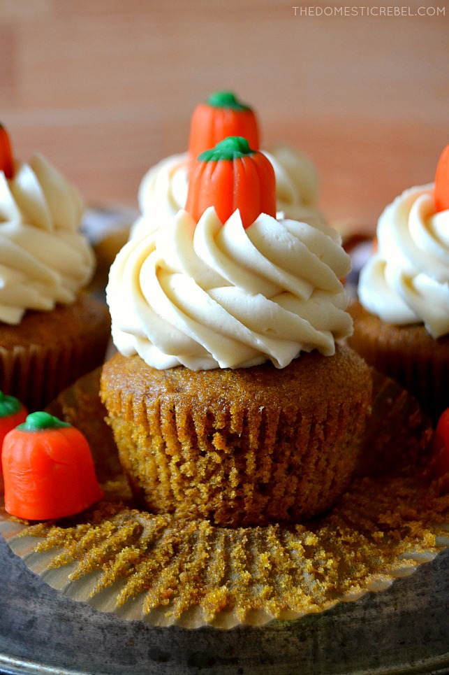 Pumpkin cupcake with wrapper peeled and a mini pumpkin candy