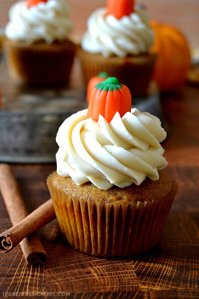 Closeup of pumpkin cupcake on wooden cutting board with cinnamon sticks