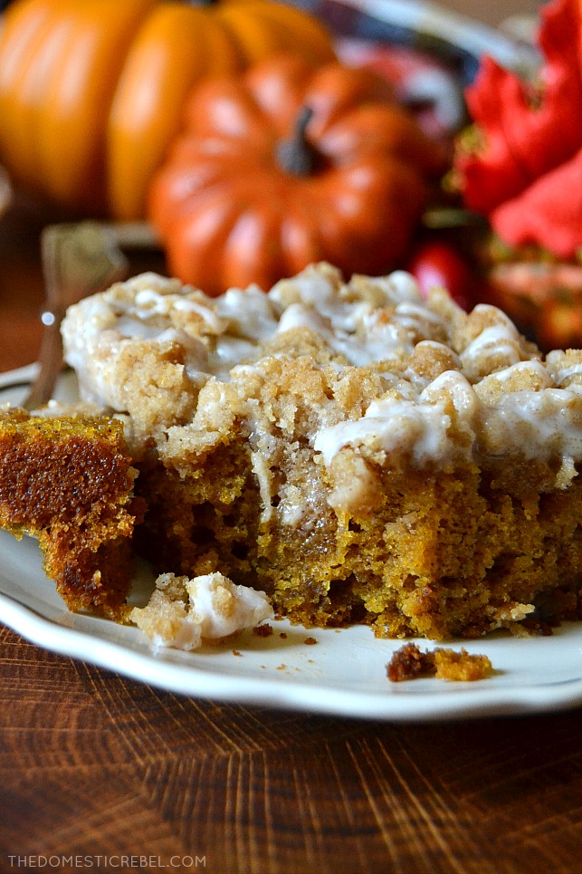 A photo of a piece of pumpkin coffee cake on a white plate with a bite missing