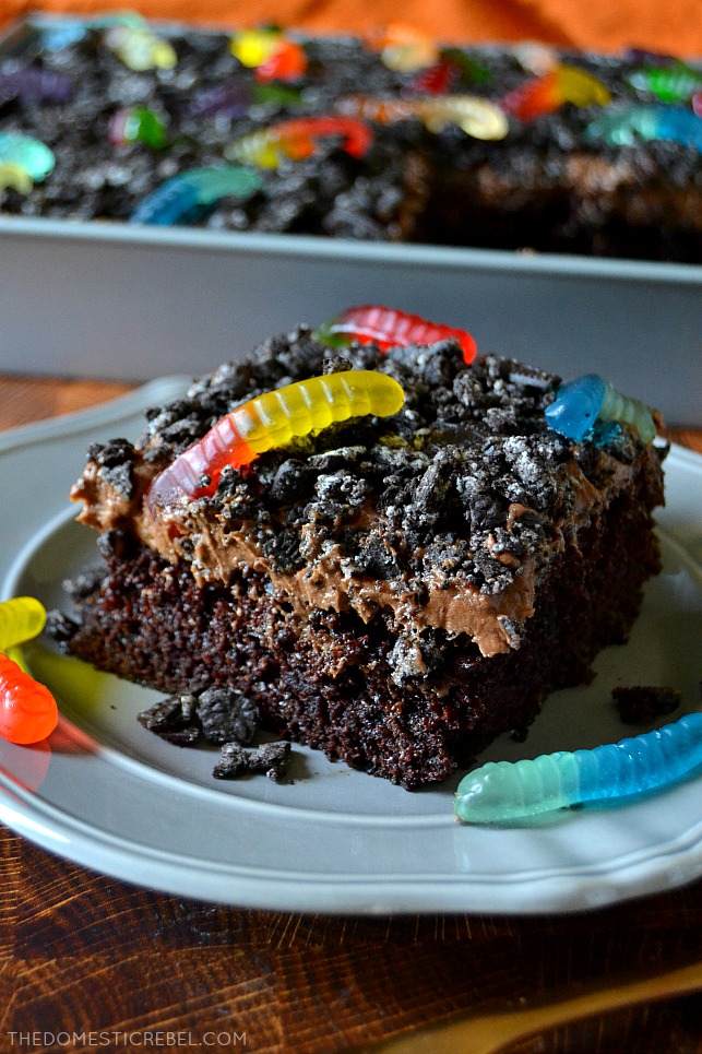 Slice of chocolate dirt cake on grey plate with gummy worms candy