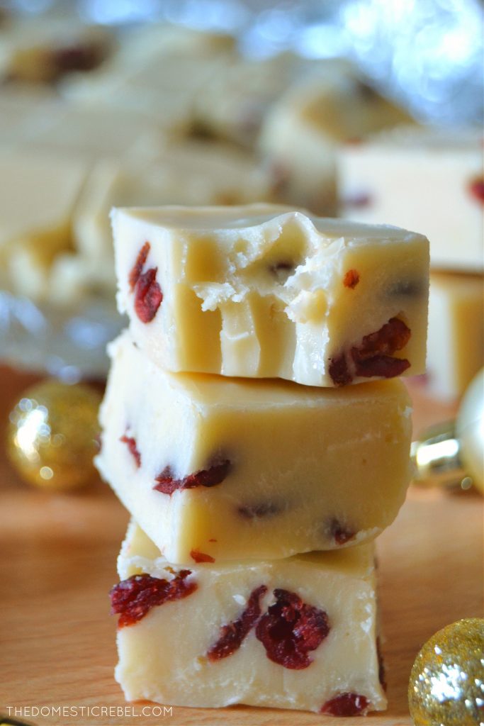 Trio of white chocolate cranberry fudge stacked with one piece missing a bite