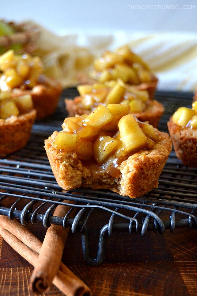 Apple crisp cookie cups on a black wire rack with a bite missing