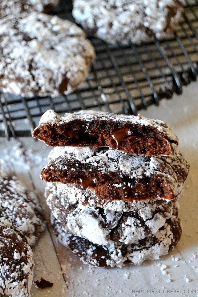 Stack of brownie crackle cookies on white wood with black wire rack in background